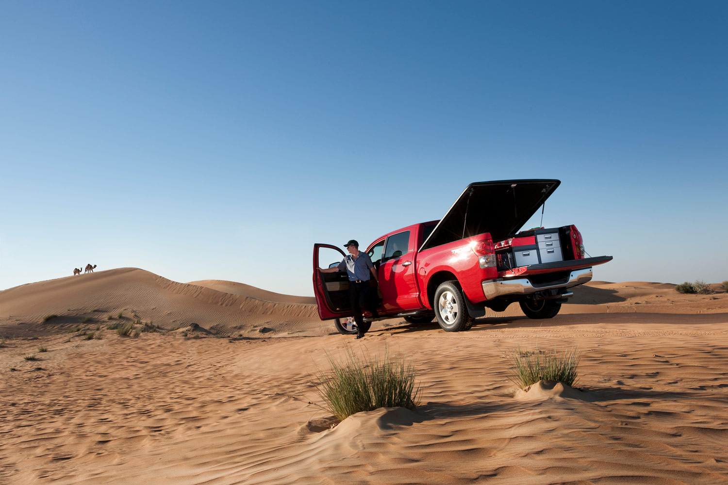 Worker's red pickup truck with modul-system racking in a desert